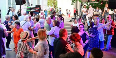 Menschen tanzen ausgelassen vor der Schlossgartenbühne zu italienischer Musik